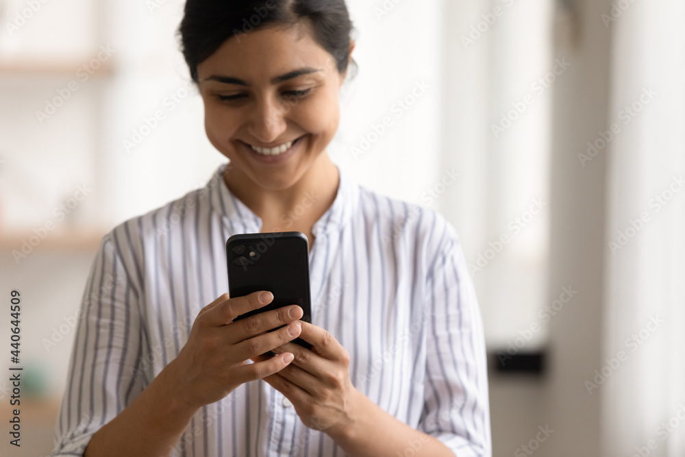 Close up of happy millennial Indian female user hold cellphone look at screen talk speak on video call. Smiling young mixed race woman use smartphone browse internet on gadget. Communication concept. Close up of happy millennial Indian female user hold cellphone look at screen talk speak on video call. Smiling young mixed race woman use smartphone browse internet on gadget. Communication concept.