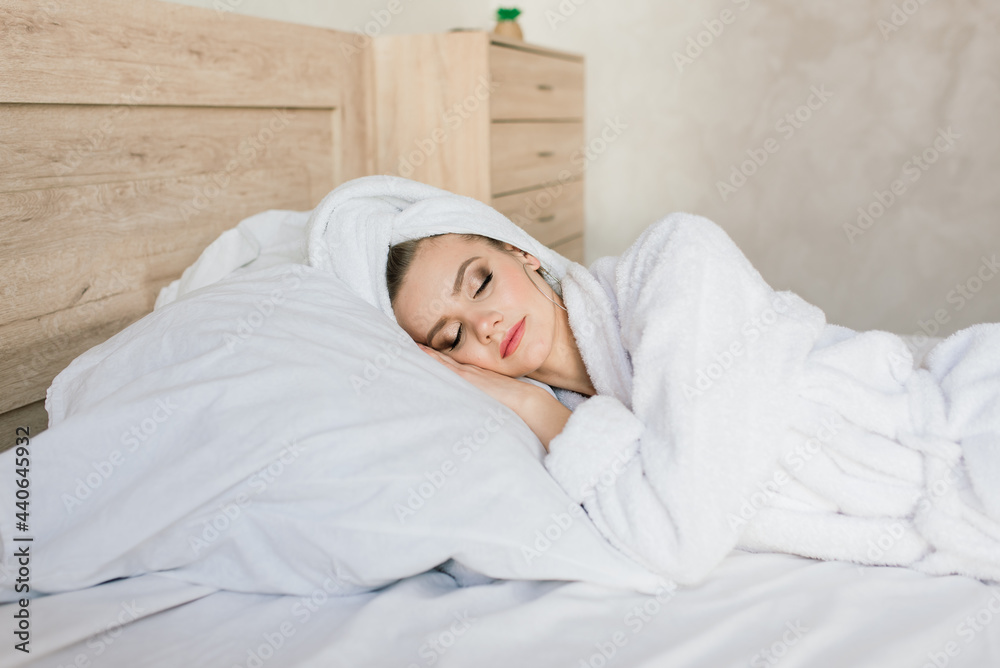 Woman in white robe stay near the window and on bed in hotel room Woman in white robe stay near the window and on bed in hotel room