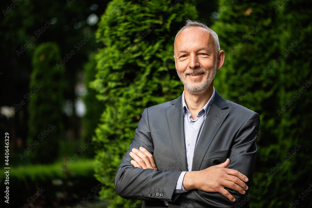 Smiling businessman in a gray suit on the background of a hedge. Smiling businessman in a gray suit on the background of a hedge.