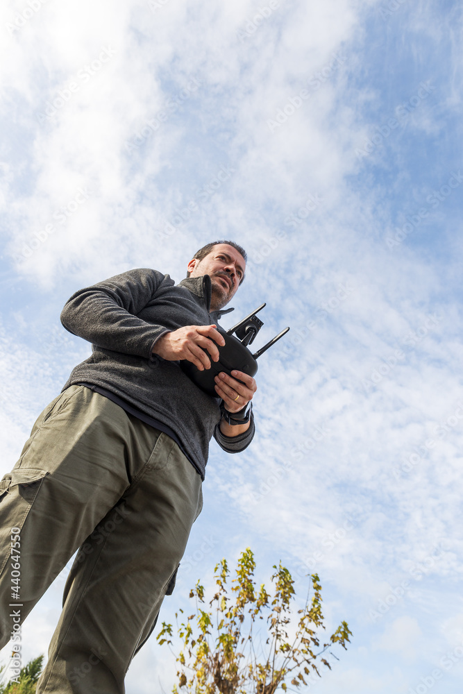 Man driving drone with remote control in hands photographed from below Man driving drone with remote control in hands photographed from below