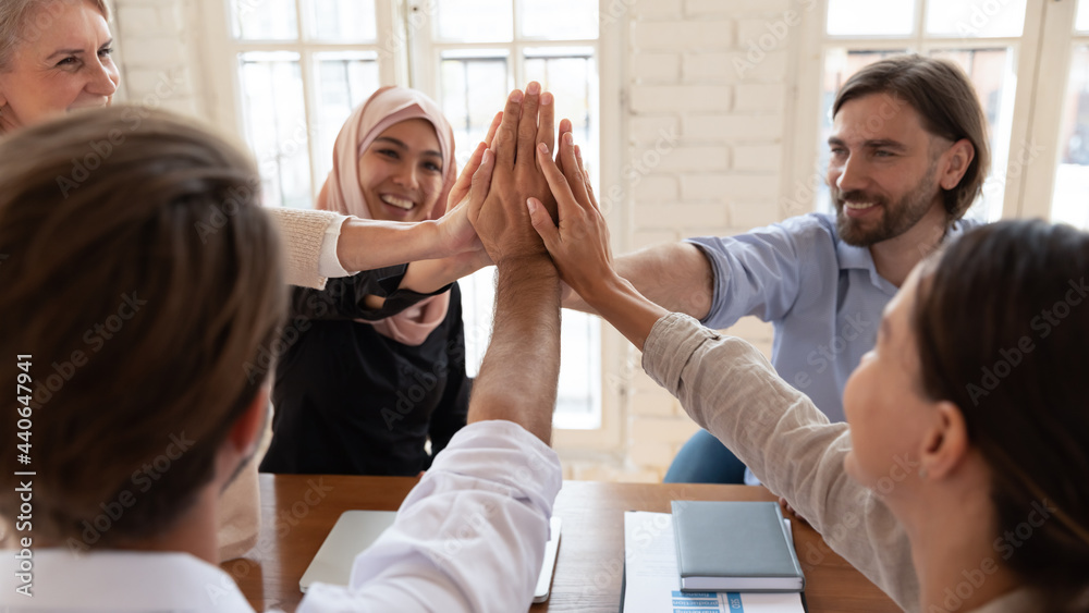 Happy diverse employees giving high five close up at meeting, sitting ...