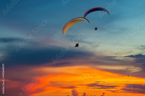 Skydiving sunset landscape of parachutist flying in soft focus. Para-motor flying silhouette with sun set. Silhouette of paraglider flying in the evening sky with sunset.