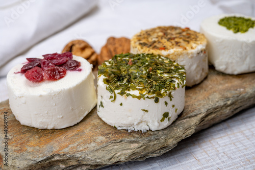 Cheese collection, variety of fresh white soft goat French cheeses with aromatic herbs, berries and green pesto