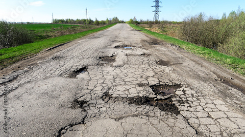 The texture of cracked old asphalt in need of repair. The road is full of holes and potholes. Pit repair