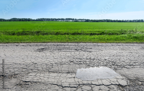 The texture of cracked old asphalt in need of repair. The road is full of holes and potholes. Pit repair