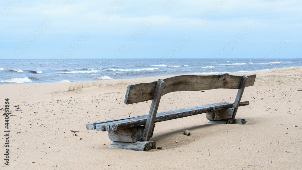 Sea view and wooden bench in the sand dunes on a windy day.