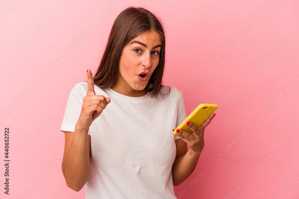 Young caucasian woman holding a mobile phone isolated on pink background having an idea, inspiration concept. Young caucasian woman holding a mobile phone isolated on pink background having an idea, inspiration concept.