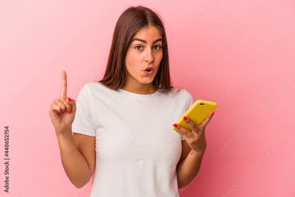Young caucasian woman holding a mobile phone isolated on pink background having some great idea, concept of creativity. Young caucasian woman holding a mobile phone isolated on pink background having some great idea, concept of creativity.