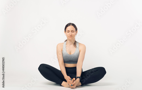 Photo of young sport woman sitting in butterfly stretching pose in studio