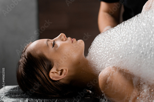 Close-up foam peeling massage for model in spa. Relaxation in Turkish hammam photo