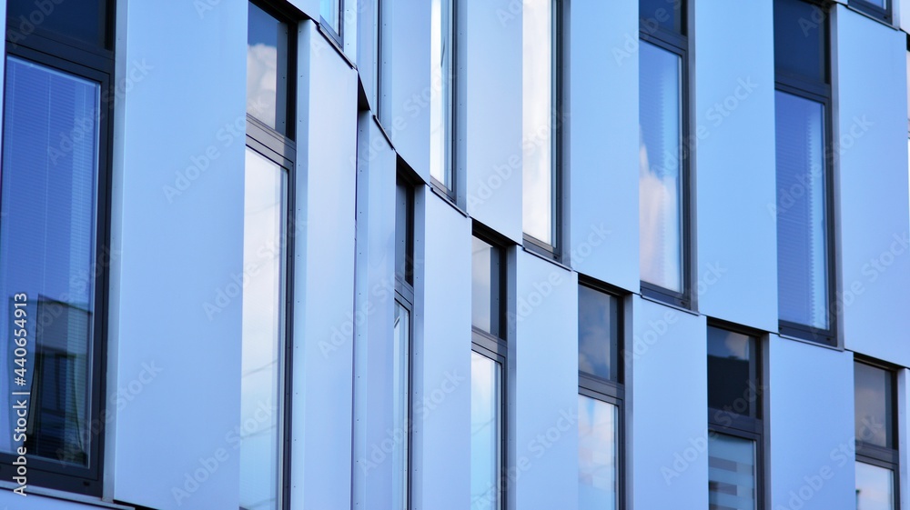 Obraz premium Abstract closeup of the glass-clad facade of a modern building covered in reflective plate glass. Architecture abstract background. Glass wall and facade detail.