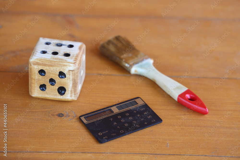 A dice with a calculator and a carpenter's brush symbolize work, passion  and sober calculation, background foto de Stock | Adobe Stock