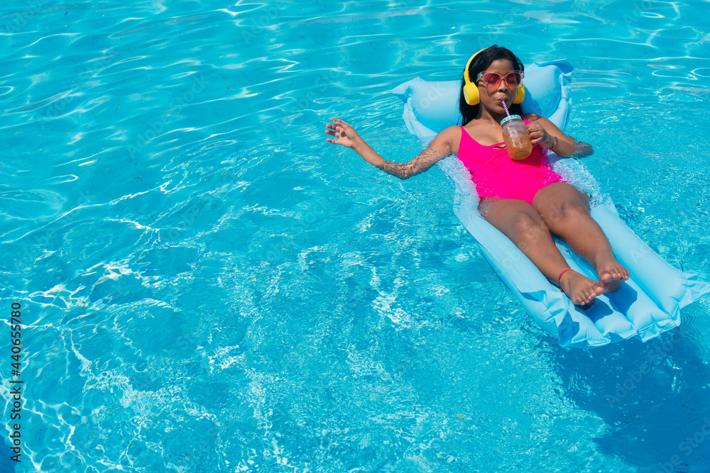 African Woman sunbathing drinking a juice in a swimming pool
