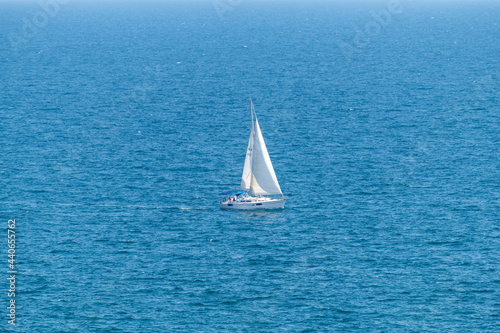 Sailboat sailing alone in vast blue Gulf of Mexico off the coast of Panama City Beach Florida