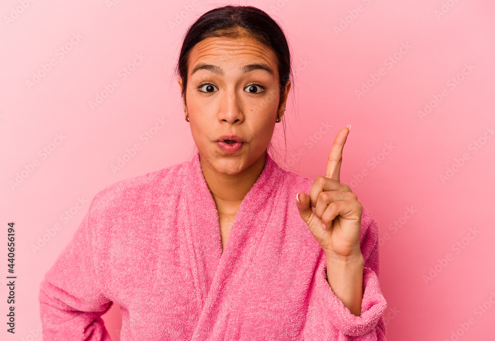 Young Venezuelan woman wearing a bathrobe isolated on pink background having an idea, inspiration concept. Young Venezuelan woman wearing a bathrobe isolated on pink background having an idea, inspiration concept.