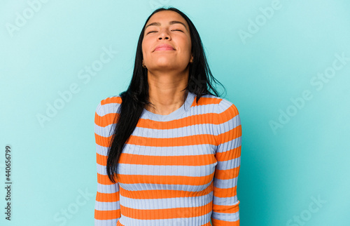 Young Venezuelan woman isolated on blue background laughs and closes eyes, feels relaxed and happy. © Asier