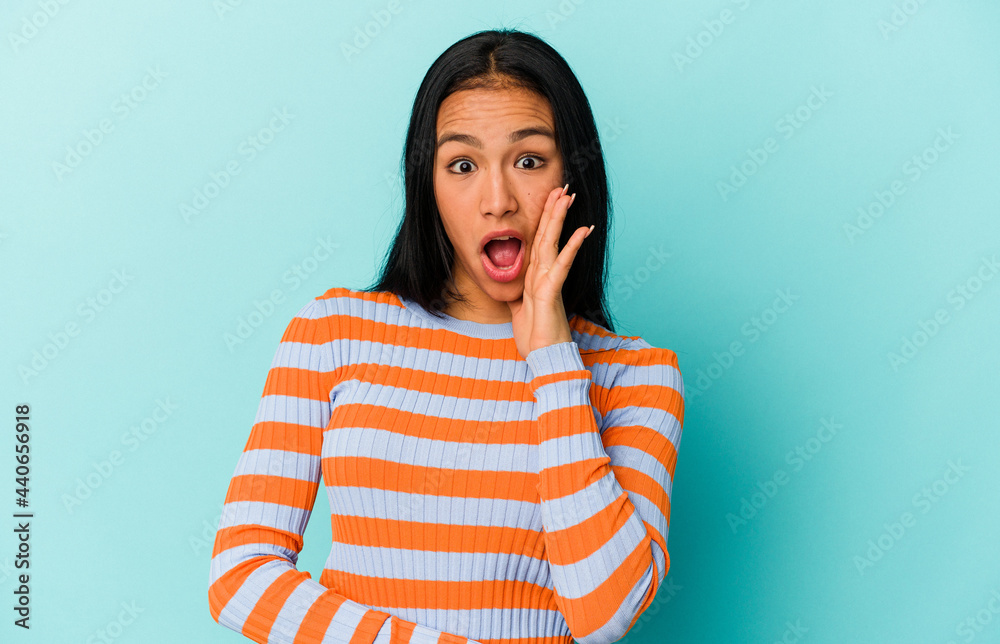Fototapeta premium Young Venezuelan woman isolated on blue background shouts loud, keeps eyes opened and hands tense.