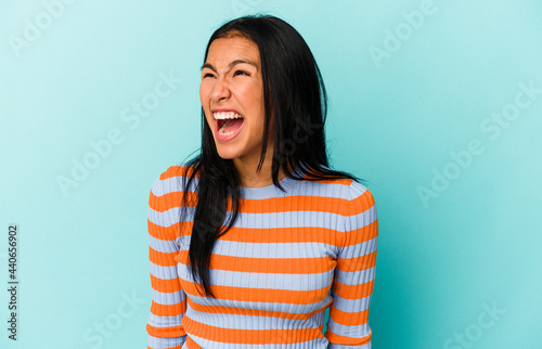 Young Venezuelan woman isolated on blue background shouting very angry, rage concept, frustrated. © Asier