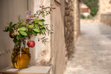 dzbanek z ziołami i owocami w otoczeniu kamiennego, śródziemnomorskiego miasteczka