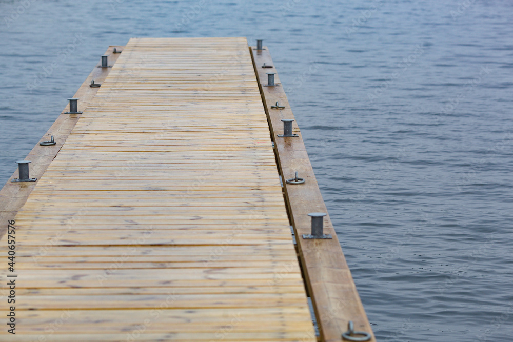 Wooden pier and grass on lake shore on sunny summer day