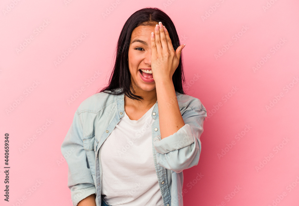 Young Venezuelan woman isolated on pink background having fun covering half of face with palm. Young Venezuelan woman isolated on pink background having fun covering half of face with palm.