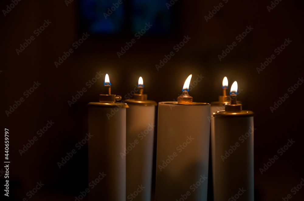 kilka płonących świec w kościele, pośród mroku - obrazy, fototapety, plakaty 