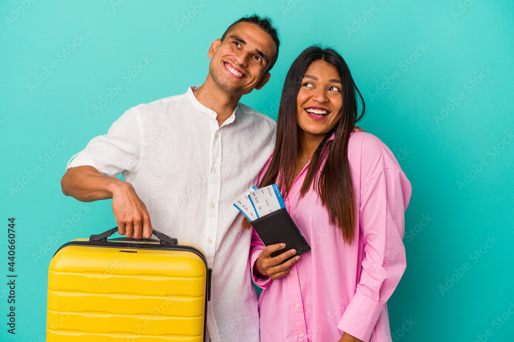 Young latin couple going to travel isolated on blue background dreaming of achieving goals and purposes