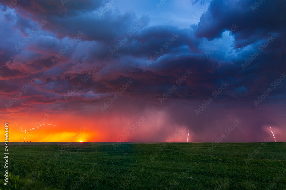 Lightning bolts strike at sunset along the Wyoming / Colorado border at sunset. The last remnants of the sun can be seen setting along the horizon with color hues of pinks, purples, reds, and oranges.