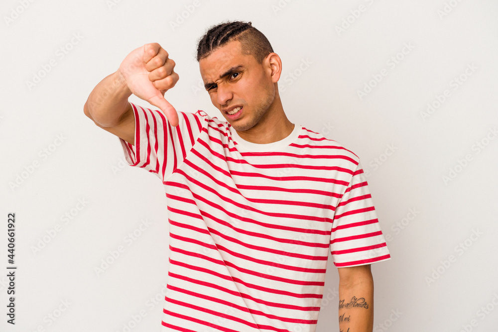 Young venezuelan man isolated on white background showing thumb down and expressing dislike. Young venezuelan man isolated on white background showing thumb down and expressing dislike.