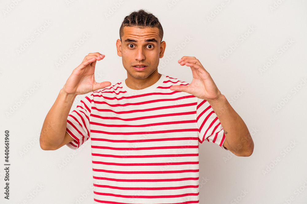 Young venezuelan man isolated on white background holding something with palms, offering to camera.