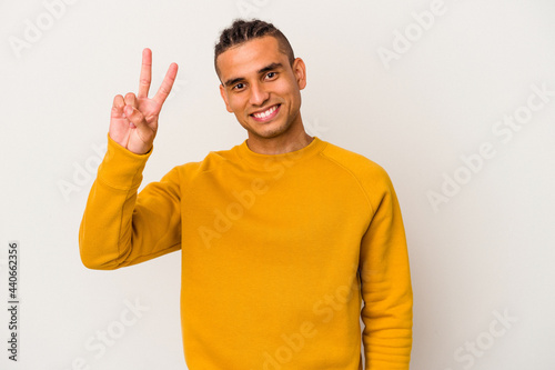 Young venezuelan man isolated on white background joyful and carefree showing a peace symbol with fingers.