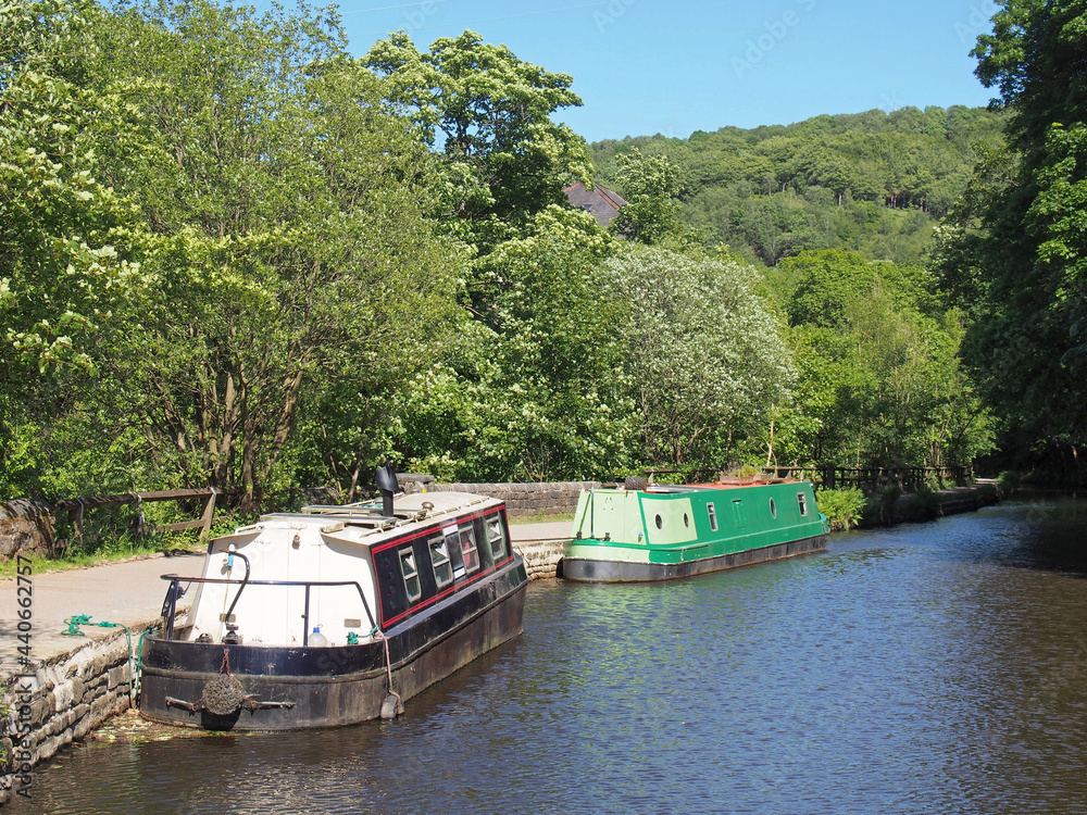 Houseboats moored along the Rochdale canal outside Hebden Bridge surrounded by trees