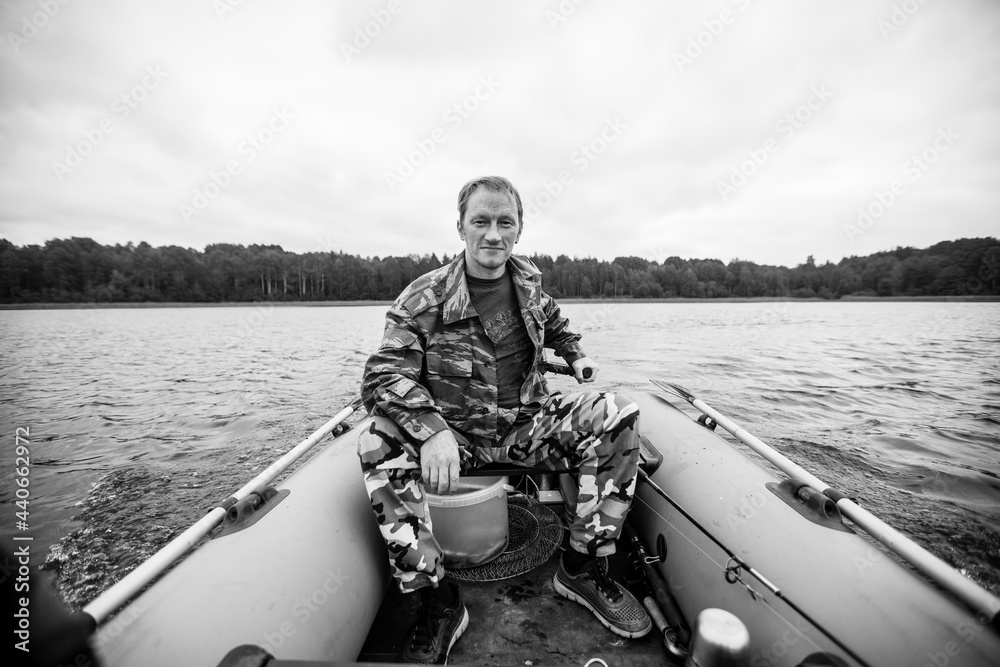 A man dressed in camouflage in a motor rubber boat. A man dressed in camouflage in a motor rubber boat.