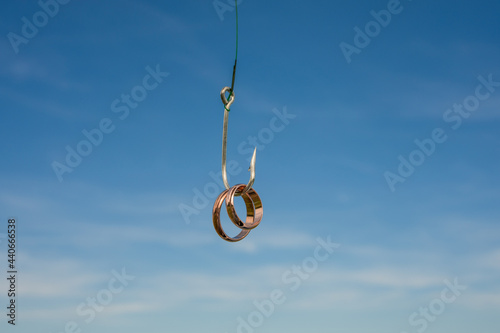 Wedding rings on a fishing hook. Marriage of convenience, divorce, alimony, division of property, trap, court law. photo