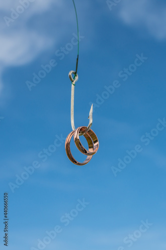 Wedding rings on a fishing hook. Marriage of convenience, divorce, alimony, division of property, trap, court law. photo