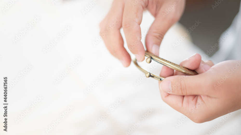 The female hand choosing a purse clasp that showing the perforated metal frame with the angled bead fastener. The accessories for purse. The female hand choosing a purse clasp that showing the perforated metal frame with the angled bead fastener. The accessories for purse.