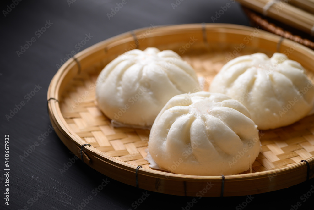 Steamed bun stuffed with minced pork on bamboo basket with black background, Asian food