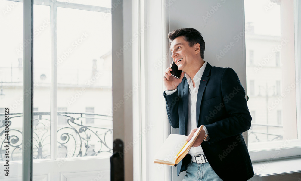 Makes a design project remotely writes down new ideas in a pencil in a diary. An adult male lawyer works in his office in a tablet and calls. Dressed in a modern business suit. Makes a design project remotely writes down new ideas in a pencil in a diary. An adult male lawyer works in his office in a tablet and calls. Dressed in a modern business suit.