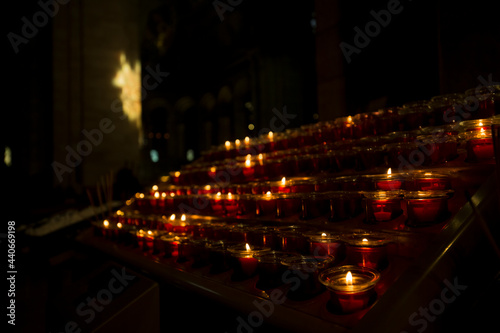 Many flaming candles shining to darkness of interior of medieval church.
