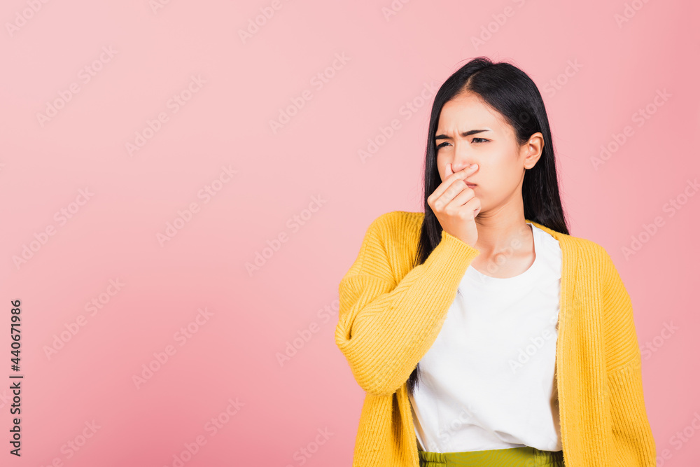 Asian beautiful young woman unhappy what a smell disgust expression squeezing nose with fingers. Female have something stinks bad smell situation, studio shot isolated on pink background, Healthcare Asian beautiful young woman unhappy what a smell disgust expression squeezing nose with fingers. Female have something stinks bad smell situation, studio shot isolated on pink background, Healthcare