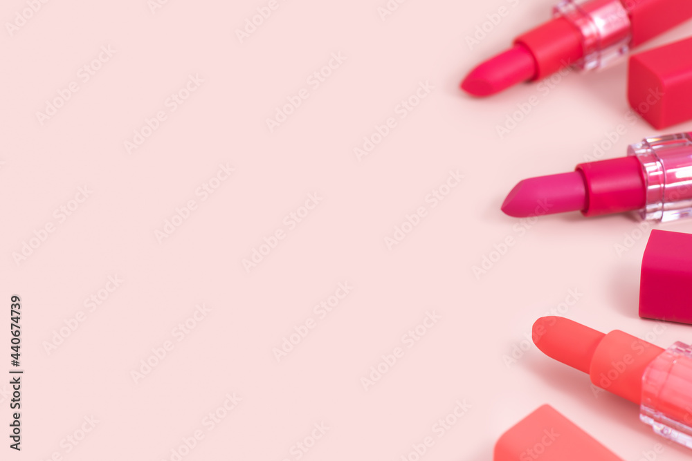 Lipstick background with copy space. Border from pink, wine and red lipsticks on a pink background. Lip cosmetics. Bright lipsticks for summertime. Lipstick background with copy space. Border from pink, wine and red lipsticks on a pink background. Lip cosmetics. Bright lipsticks for summertime.