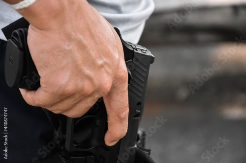 Automatic 9mm pistol holding in hand at the holster, it's ready to pull out and ready to shoot at the target ahead, concept for security profession and shooting sport around the world.