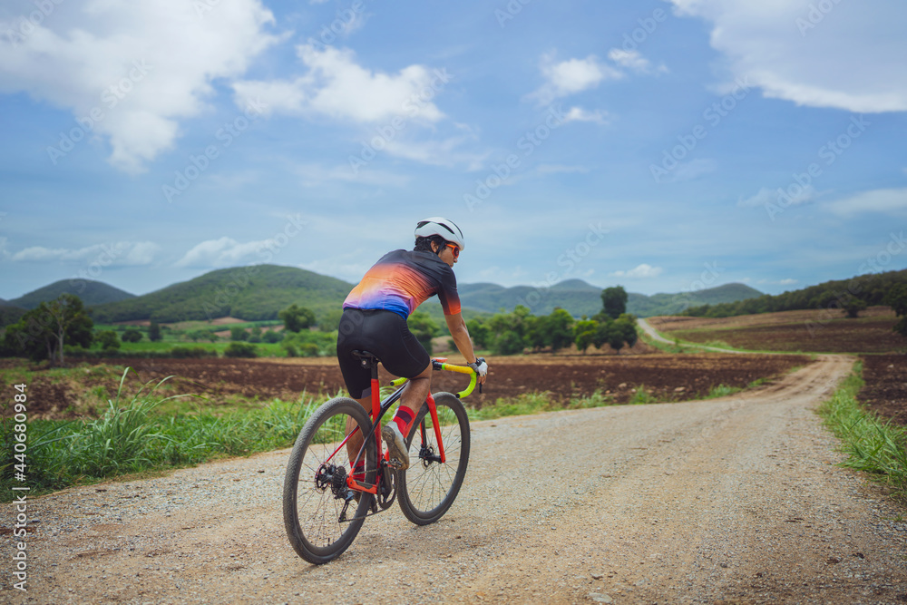 Asian man cycling on gravel road