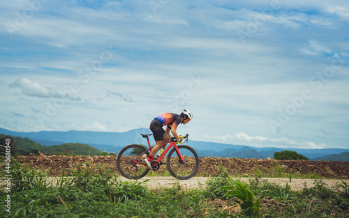 Asian man cycling on gravel road.