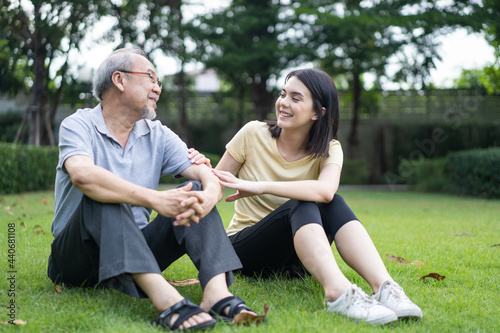 Asian young girl daughter enjoy talk to senior grandfather in garden.