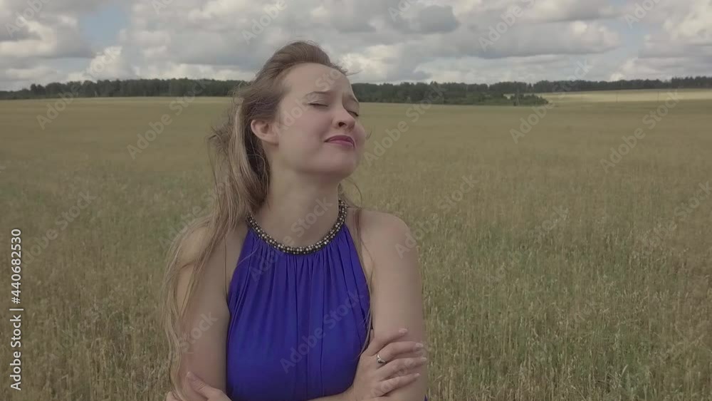 a girl in a blue dress performs a sad song in a field. Singing in nature. Shooting the clip outdoors. face close-up a girl in a blue dress performs a sad song in a field. Singing in nature. Shooting the clip outdoors. face close-up