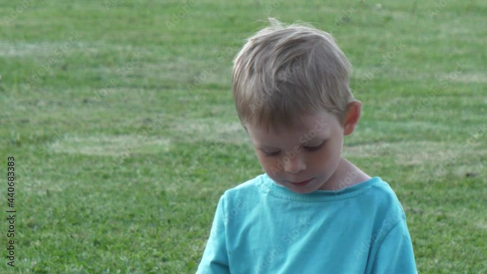 Young caucasian boy standing shy but happy isolated on green grass Young caucasian boy standing shy but happy isolated on green grass