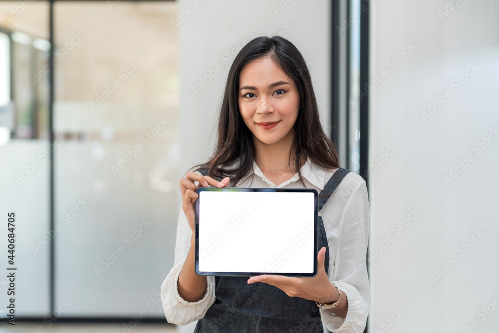 Front view of Asian businesswoman standing holding tablet blank white screen at the office. Looking at the camera. Front view of Asian businesswoman standing holding tablet blank white screen at the office. Looking at the camera.