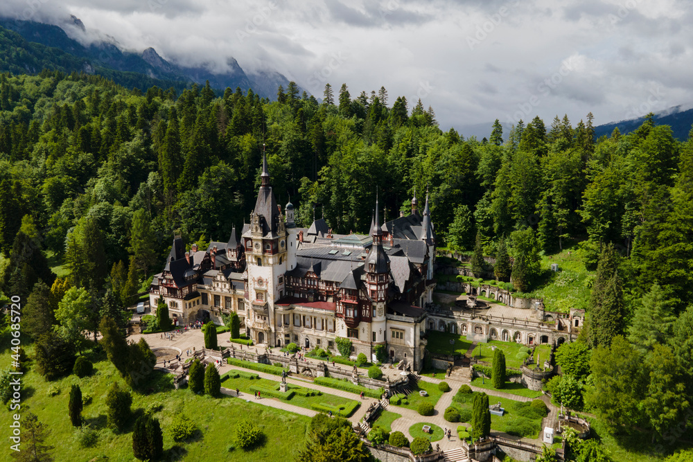 Fototapeta premium Aerial drone view of Romanian Pelesh castle, royal residence and museumin sun and fog