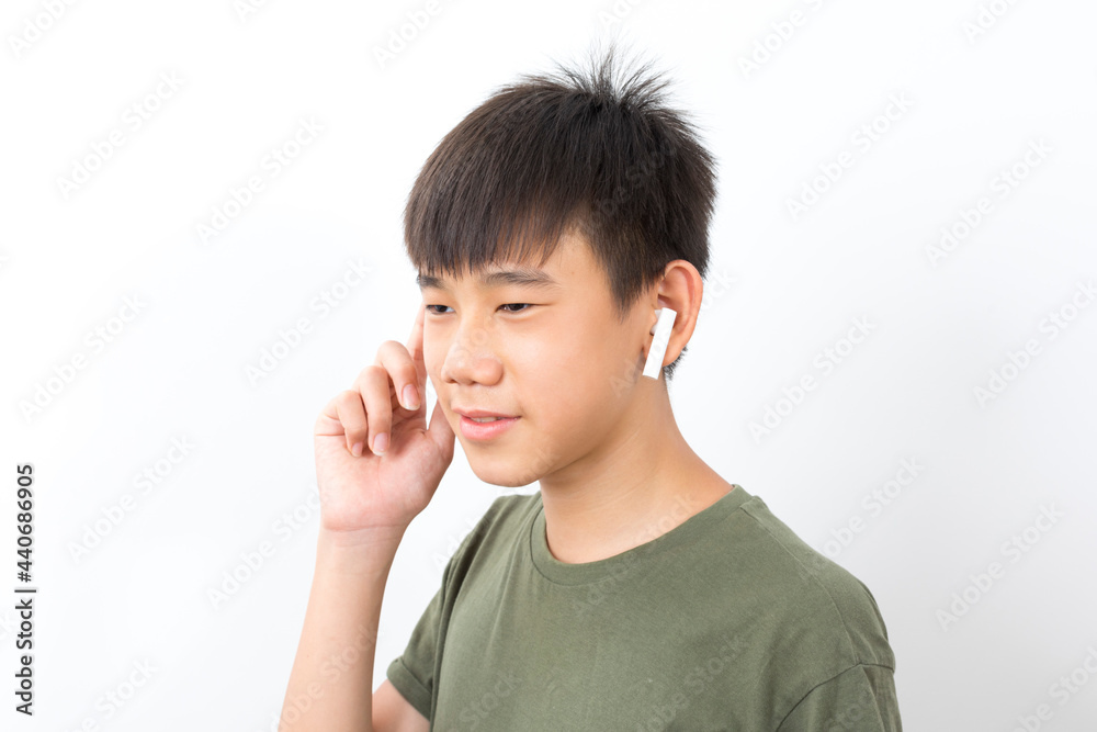 joyful Asian boy 10-12y wearing earpods smiling on white background. joyful Asian boy 10-12y wearing earpods smiling on white background.
